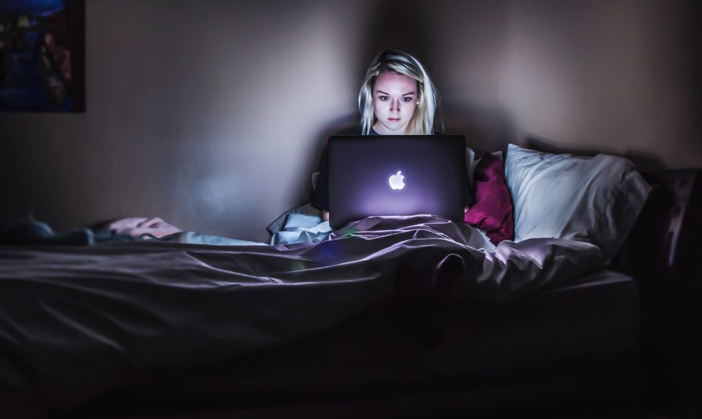 femme dans son lit qui recherche des offres de vol sur mac à 3h du matin